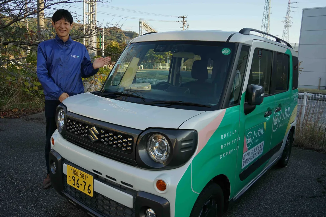 町の取り組みを周知するためにラッピングされた公用車と朝日町「みんなで未来！課」の寺崎壮課長代理の写真