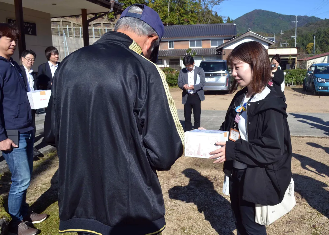 実証実験で住民に荷物を渡す竹内さんの写真